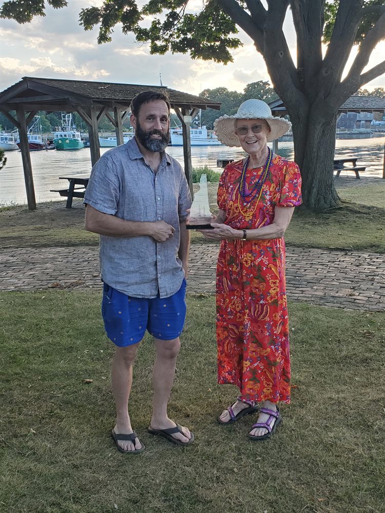 Michael Derhammer and Joan Hamblet standing by the water holding the Democracy Award
