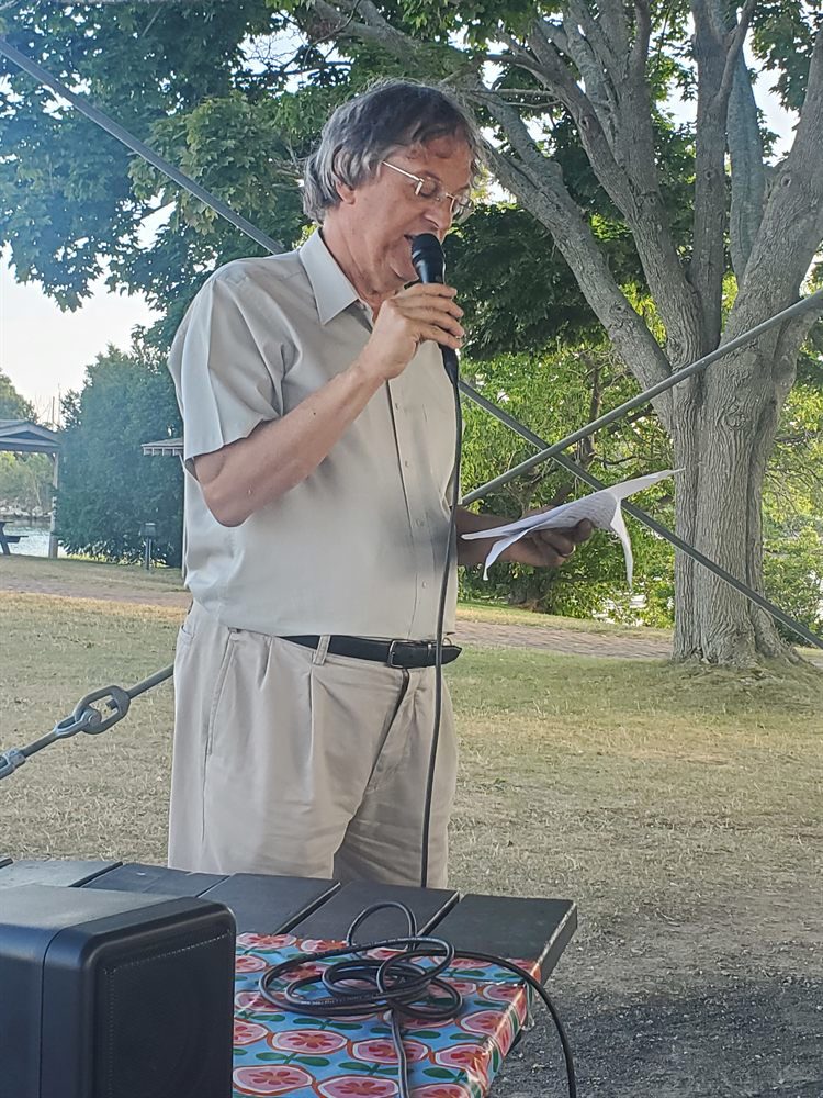 Damon Thomas at the microphone with a printed page in his hand